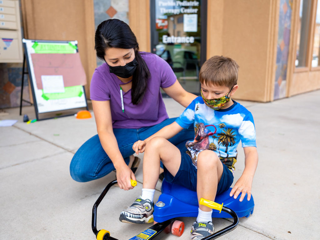 child riding roller racer with child care worker